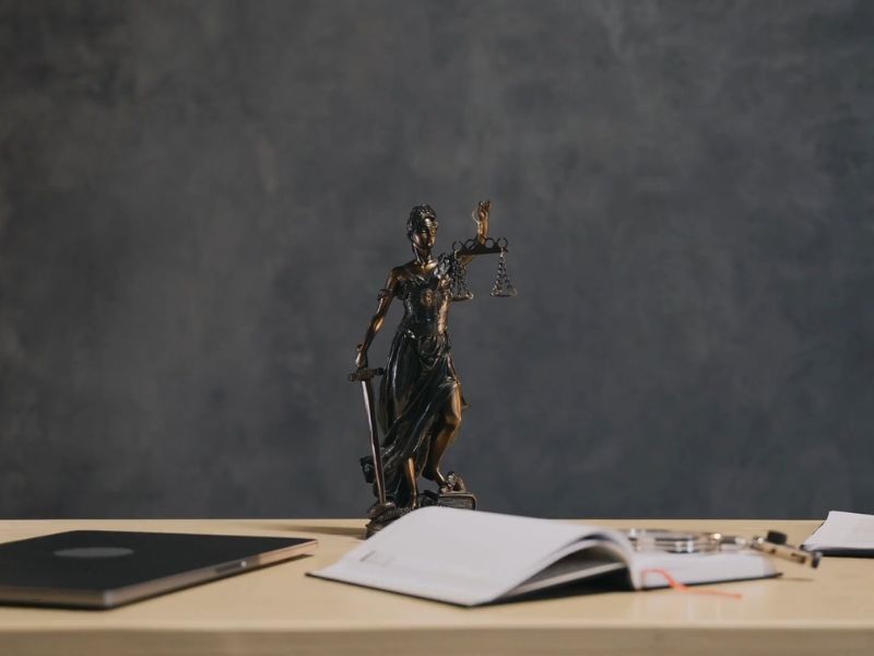 prikaz sudske figurice, laptopa i knjige na stolu