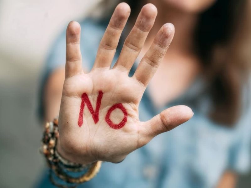 prikaz žene koja je pružila dlan na kom piše crvenim slovima reč NO